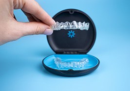 An orthodontist holding clear aligners and a carrying case