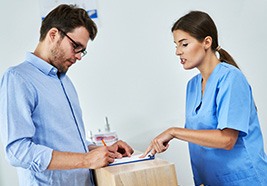 A man with glasses paying the cost of SureSmile