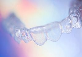 Closeup of clear aligners with rainbow colors in the background