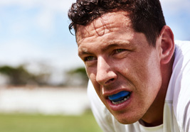Man on a soccer field wearing a mouthguard over his teeth
