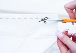 Person opening a paper package with scissors