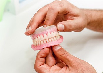 Technician holding dentures in Lewisville, TX