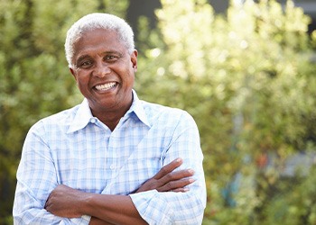 Senior man outside smiling with arms folded