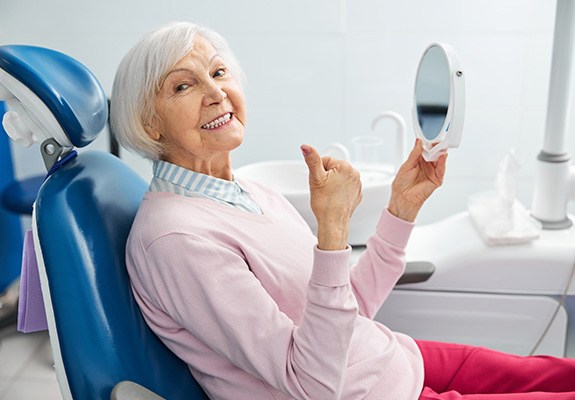 Senior woman in dental chair with handheld mirror