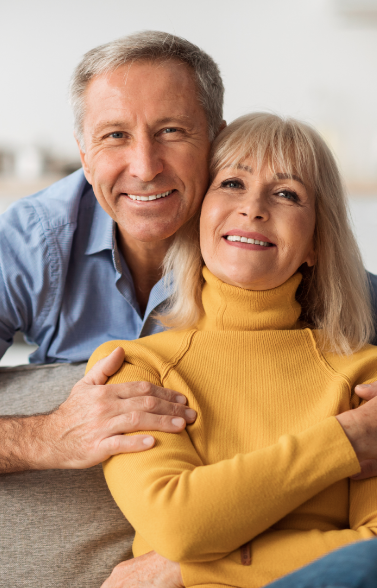 Woman sitting on couch with man hugging her from behind