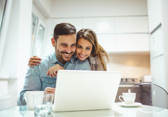 Man and woman smiling and looking at laptop