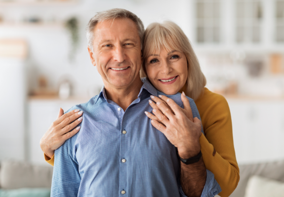 Senior man being hugged from behind by senior woman